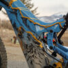 A close up of the painted frame on an Optibike E-Bike, showing the hand painted wolf howling at the sky, painted in vibrant gold color.
