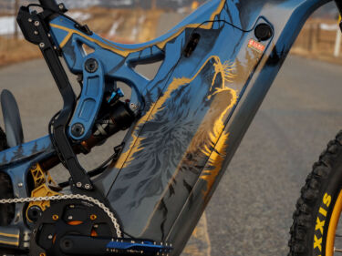 A close up of the painted frame on an Optibike E-Bike, showing the hand painted wolf howling at the sky, painted in vibrant gold color.