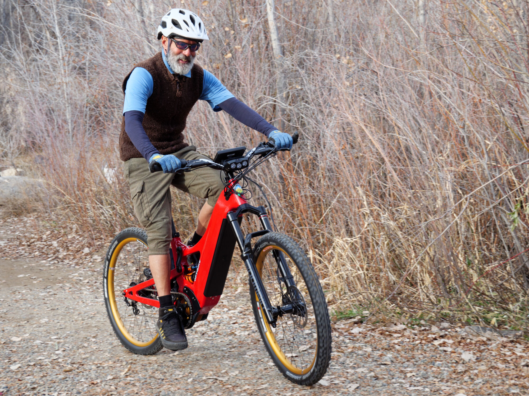 Rider testing the high-speed capability of the Optibike Altus electric mountain bike on a trail, demonstrating stable handling at speed with motion blur.