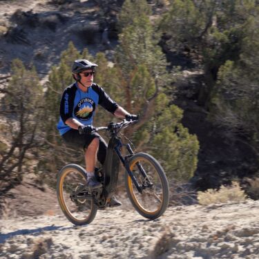 The Optibike G2 climbing up a steep hill, with the rider looking like they're having an easy time.
